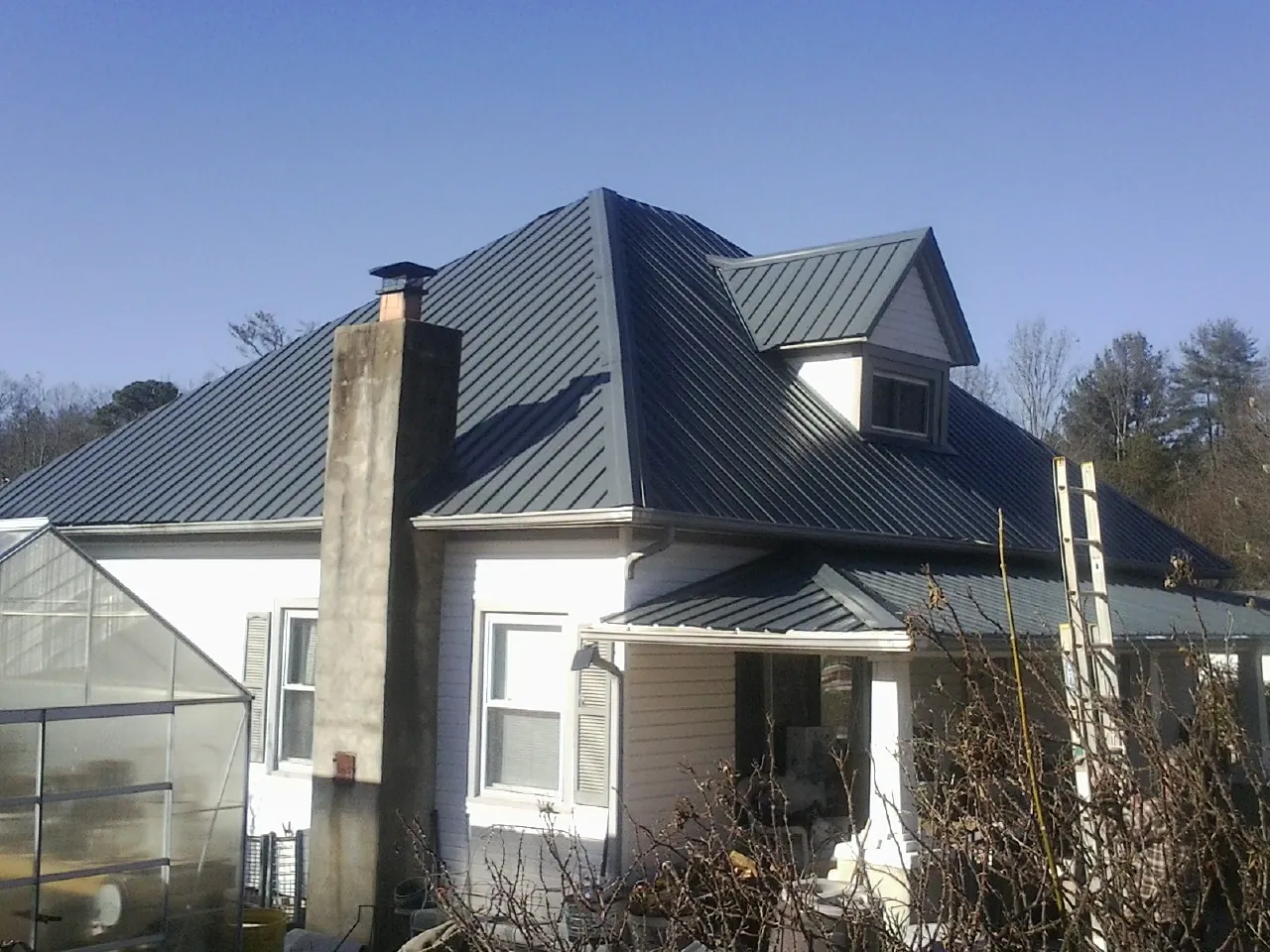 Dark blue standing seam metal roof on a white farmhouse with dormer — Slate & Tile Roof Repair by Roofing Brothers in Glen Lyon
