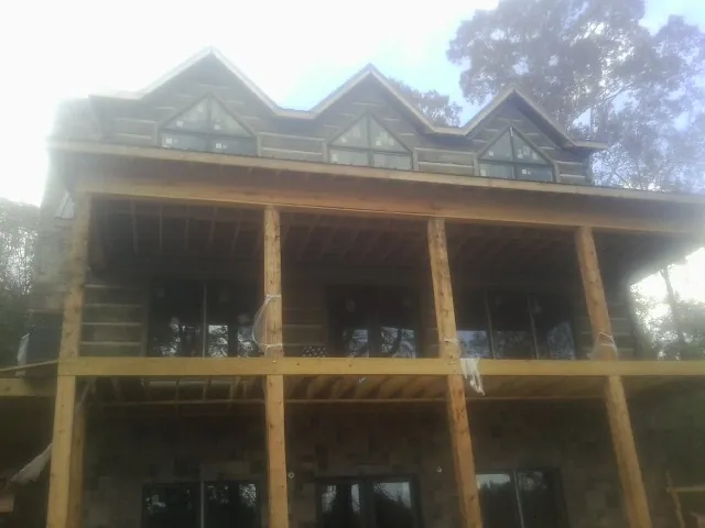 Dormers and porch framing on a large log home under construction — Roof Coating work by our crew in Glen Lyon