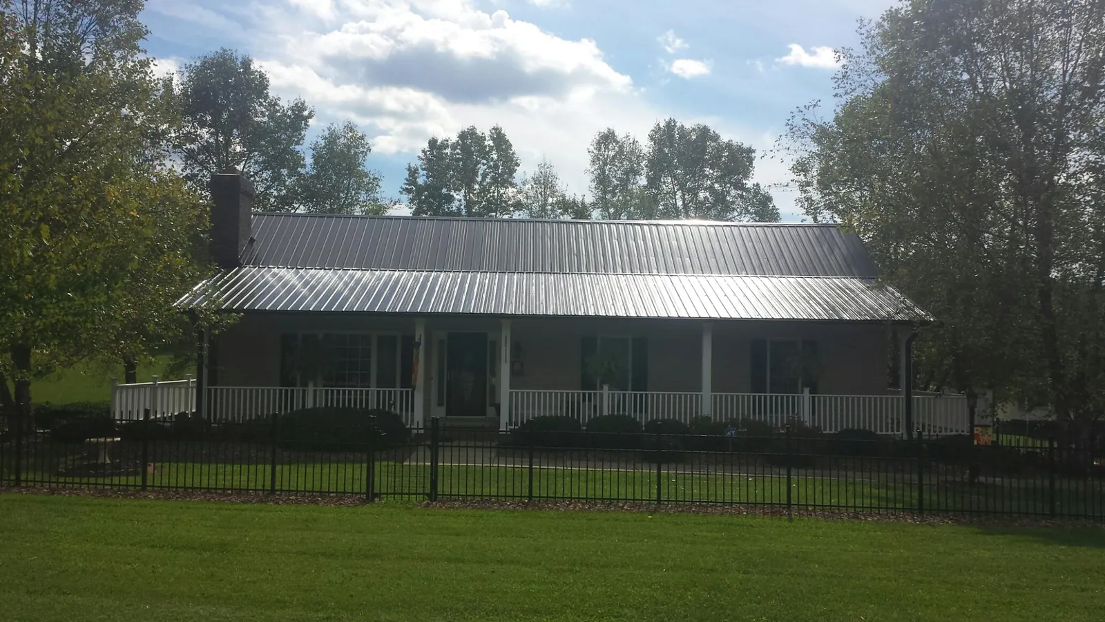 Gray metal roof on a brick ranch with a full width front porch — Gutter Guard Installation work by our crew in Glen Lyon