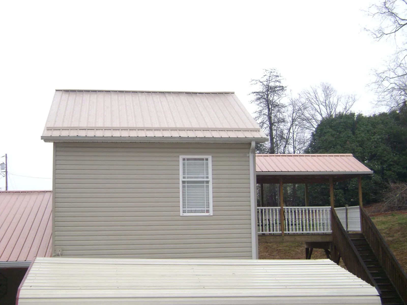 Tan metal roofs on a two story addition and attached porch, from a Roof Replacement job in Glen Lyon