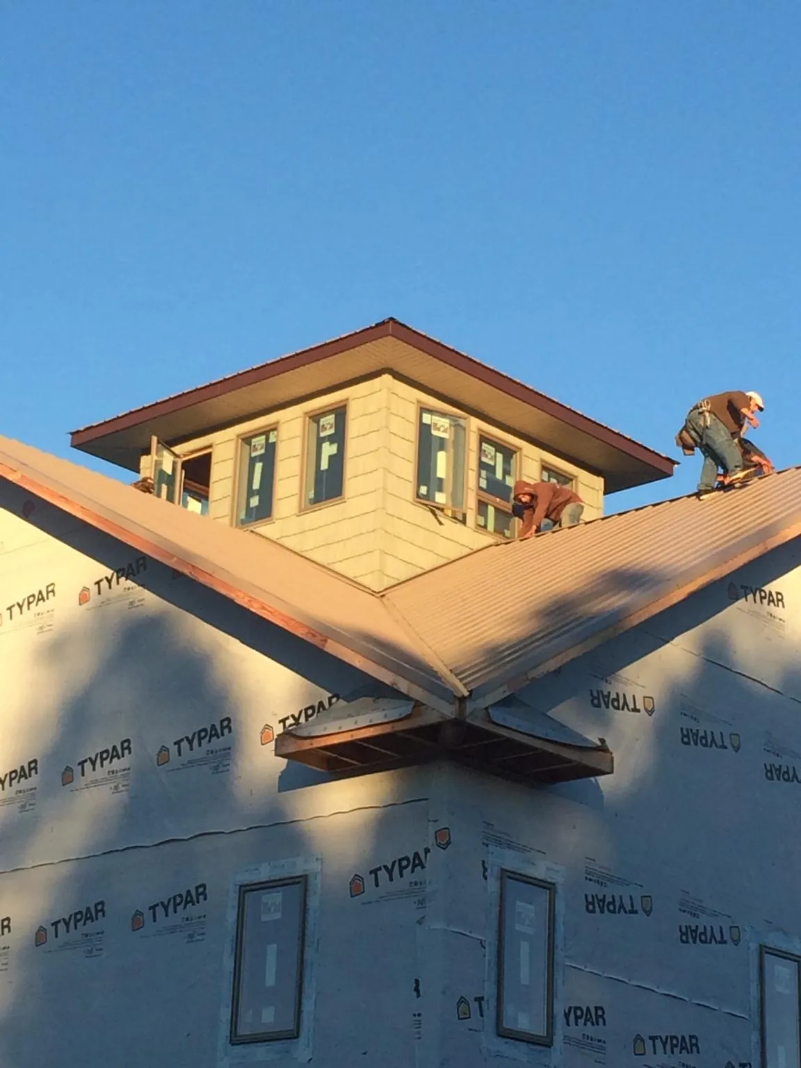 Roofers working around a rooftop cupola on a new metal roof at sunset — Roof Waterproofing in Glen Lyon by Roofing Brothers